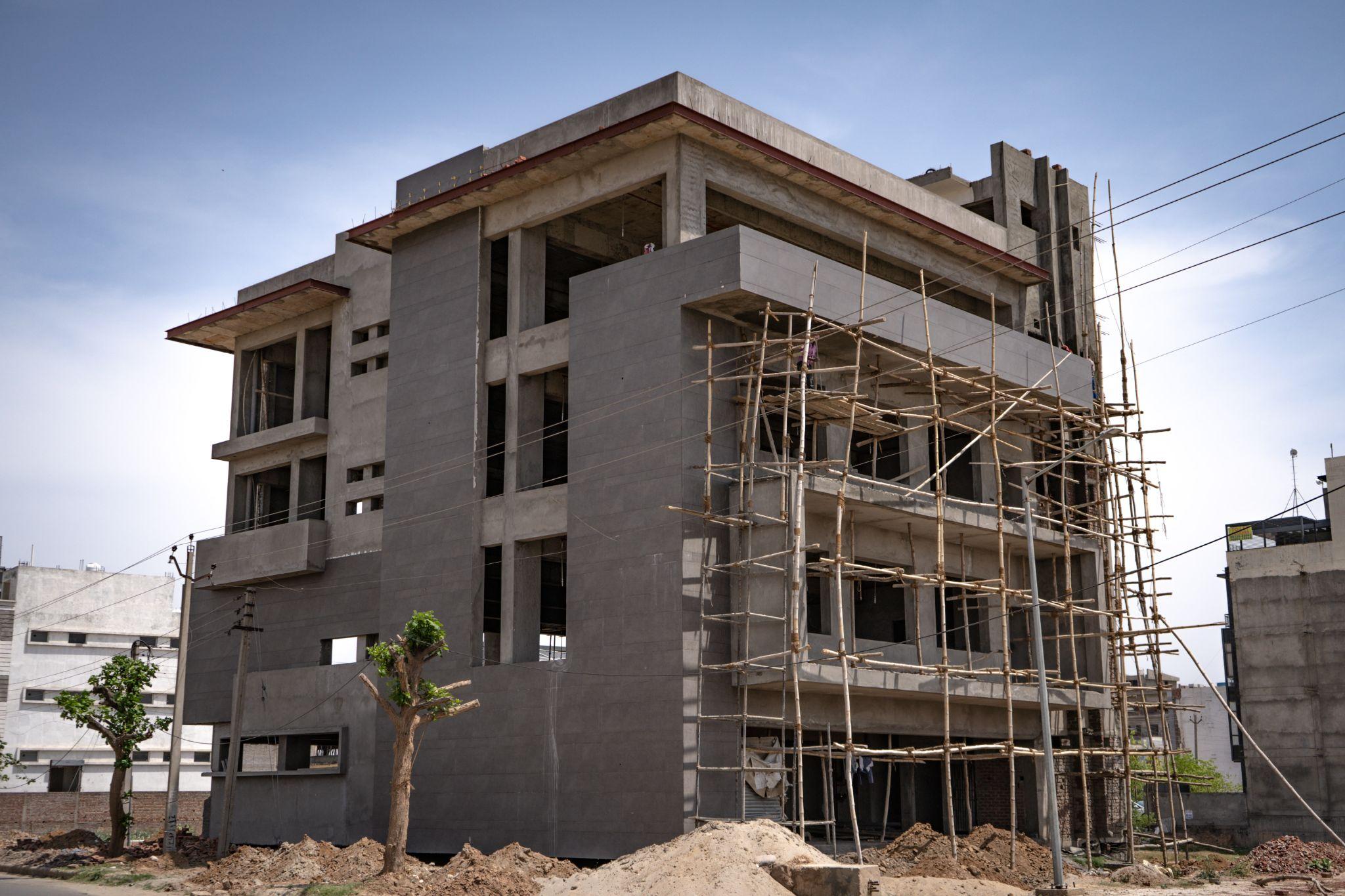 Ground view of a gray 4-story building under construction