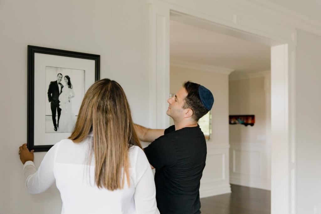 A Couple Hanging a Framed Wedding Picture on a Wall
